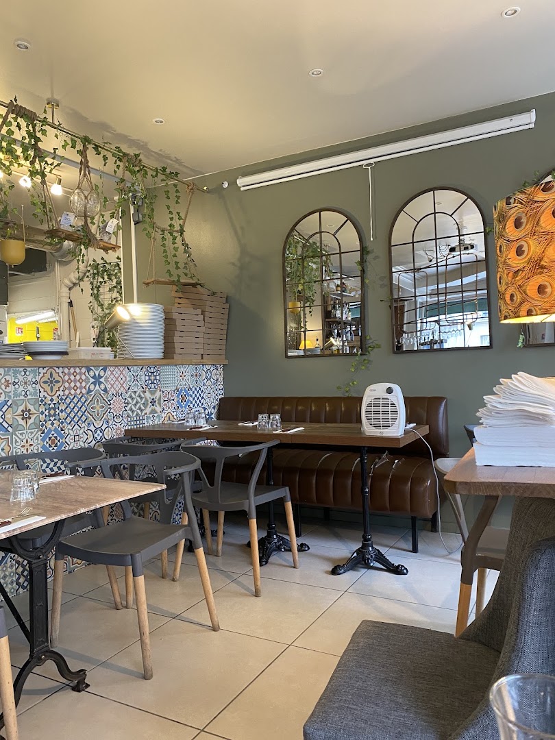 La salle aux murs verts avec ses tables vides et ses miroirs