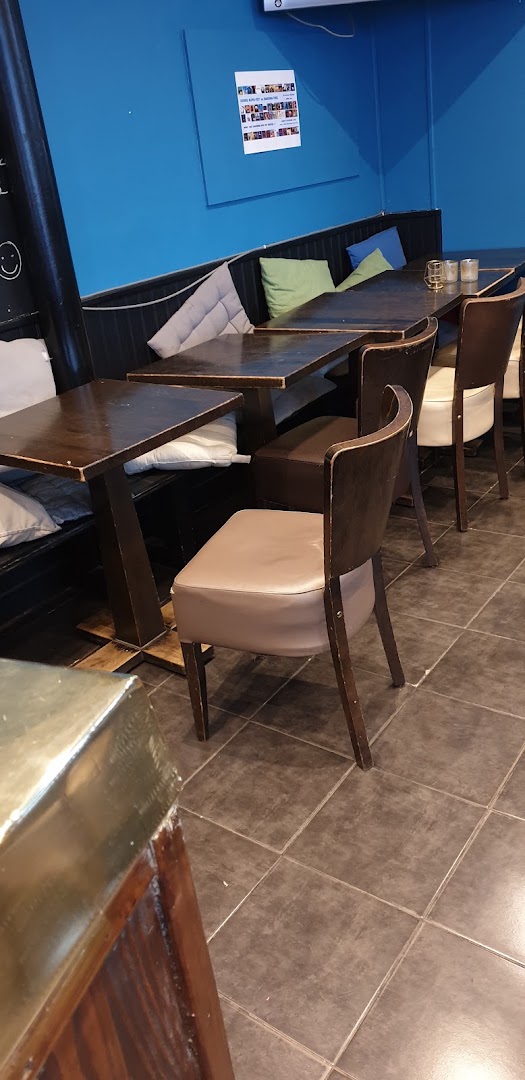 Une banquette bleue avec ses tables et ses chaises