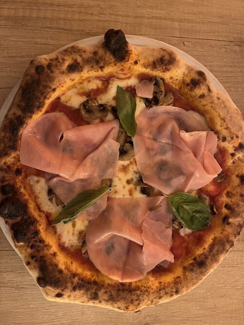Une pizza garnie de jambon, champignons et basilic